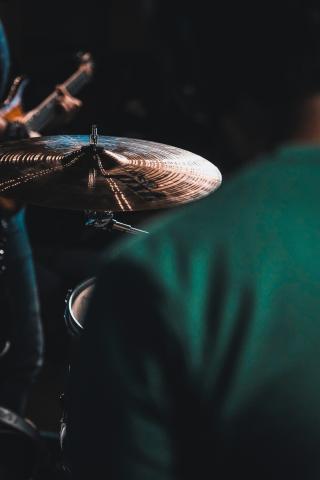 Photographie d'un homme vue de dos devant une cymbale