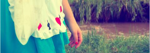 Main d'une personne avec une robe alice au pays des merveilles