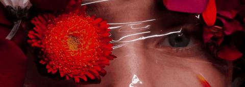 Photo d'une femme dont on voit le visga derrière un plastique transparent, avec des fleurs et des pétales devant. La photo illustre la claustrophobie, qui est le nom de la photo
