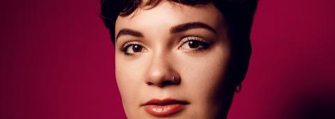 Portrait de Léane Alestra avec un fond rouge uni.