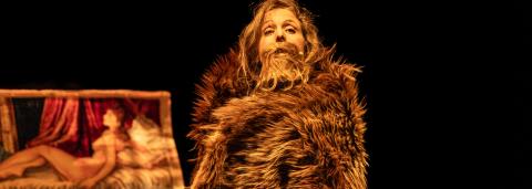 photo de la comédienne Blanche Rérolle avec un manteau de fourrue et une moustache sur scène pour le spectacle Nos Poils.
