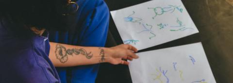 Une personne avec un crayon dans la main avec des feuilles devant elle dessine des mouvements de danse