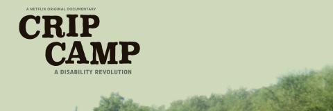 Affiche du film "CRIP CAMP", Deux jeunes garçons sont au centre de l’image, sur une route d’un camp de vacances entouré de bâtiments blancs et de nature verdoyante. L’un est assis dans un fauteuil roulant, souriant, vêtu d’un t-shirt blanc et d’un pantalon noir. L’autre, debout derrière lui, torse nu et tenant une serviette sur l’épaule, pousse le fauteuil.