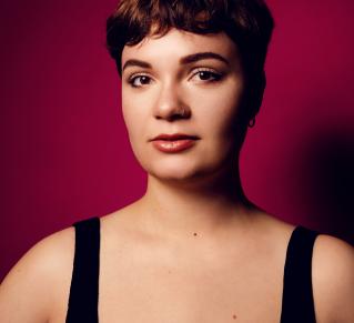 Portrait de Léane Alestra avec un fond rouge uni.