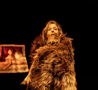 Photo de la comédienne Blanche Rérolle avec un manteau de fourrue et une moustache sur scène pour le spectacle Nos Poils