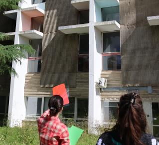 Manon Giovani, étudiante en Master médiation du Patrimoine lors d'une visite des oeuvres du campus Villejean, tenant dan ss amain des calques de couleur, pour présenter une oeuvre face à elle.