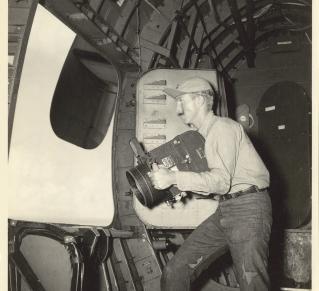 Photographie noir et blanc de 1946, montrant un photographe à bord d'un avion. 