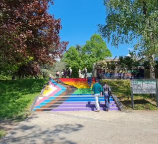Des personnes montent les escaliers peint au couleurs du drapeau LGBTQIA+ de l'Université Rennes 2, sur le mûr en haut des marches on lit le message tagué "Nos fiertés plus fortes que leur haine"