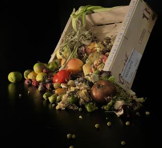 Photographie de fruits et légumes tombant d'une cagette en bois sur fond noir