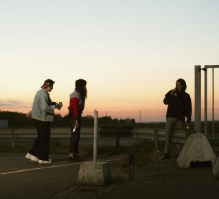 Trois personnes dans la rue, sur fond de nuit tombante