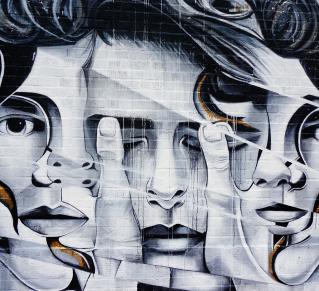 Une fresque de street art montrant trois visages de femmes en noir et blanc