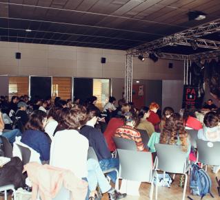 Photo où on voit une salle remplie d'étudiants et étudiantes écoutant des intervenantes et intervenants
