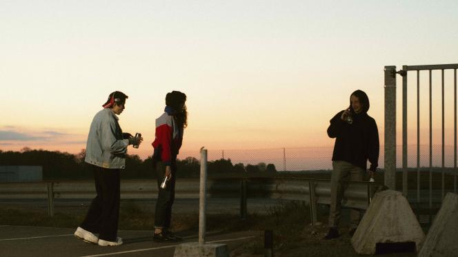 Trois personnes dans la rue, sur fond de nuit tombante