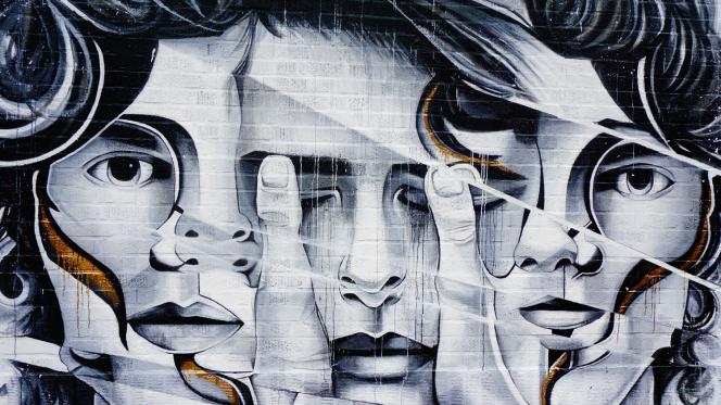 Une fresque street art montrant trois visages de femmes en noir et blanc