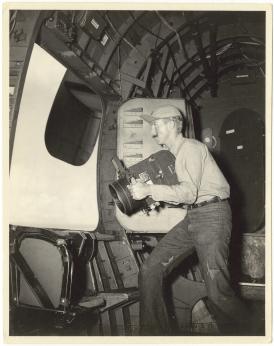 Photographie noir et blanc de 1946, montrant un photographe à bord d'un avion. 