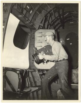Photographie noir et blanc de 1946, montrant un photographe à bord d'un avion.