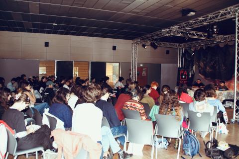 Photo où on voit une salle remplie d'étudiants et étudiantes écoutant des intervenantes et intervenants