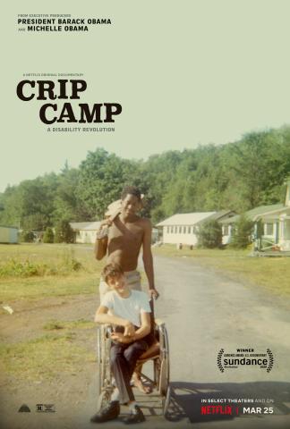 Affiche du film "CRIP CAMP", Deux jeunes garçons sont au centre de l’image, sur une route d’un camp de vacances entouré de bâtiments blancs et de nature verdoyante. L’un est assis dans un fauteuil roulant, souriant, vêtu d’un t-shirt blanc et d’un pantalon noir. L’autre, debout derrière lui, torse nu et tenant une serviette sur l’épaule, pousse le fauteuil.