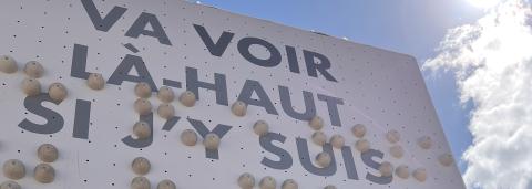 en haut du mur est écrit la phrase "Va voir là-haut si j'y suis"