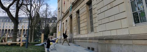 Photographie qui montre la deventure de l'hôtel pasteur. On y voit un bâtiment avec de grande fenêtres, quelques marches devant. Deux personnes tirent des draps noués ensembles d'une des fenêtres du deuxième étages. 