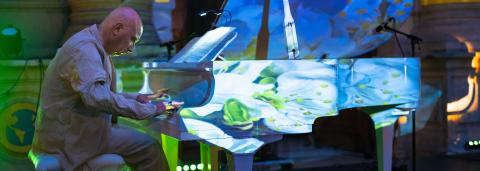 Patrick Scheyder jouant du piano sur une scène en costume blanc