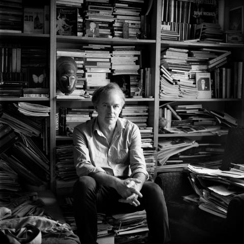 Un homme assis devant une bibliothèque