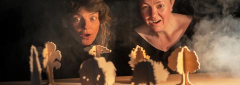 Deux femmes regardent des figurines en carton placés devant elles.