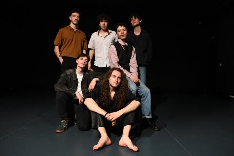 MoodRline, groupe de six jeunes hommes posant ensemble sur une scène sombre, éclairés par un projecteur.