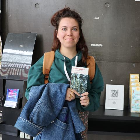 Bérénice Briand, lauréate du concours "Faites court !" 2026, tenant le recueil de textes lauréats dans ses mains.