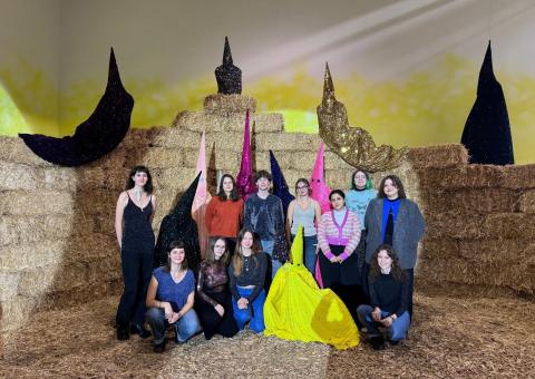 Photo des étudiantes MAE lors d'une exposition de Romuald Jandolo avec des bottes de paille en fond et des personnages costumés en paillettes.