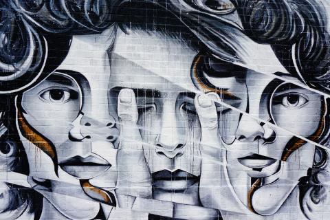 Une fresque street art montrant trois visages de femmes en noir et blanc